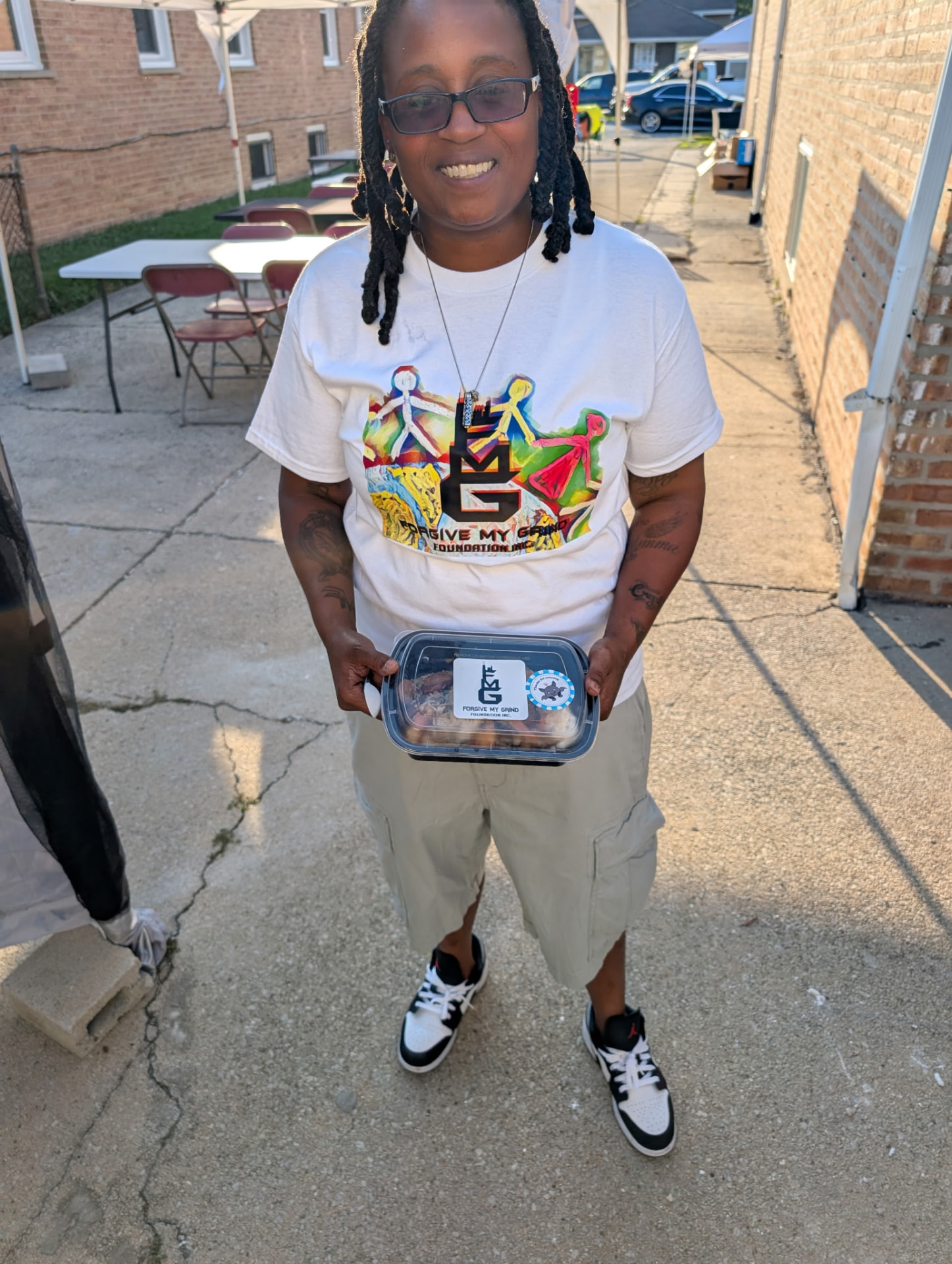 A neighbor smiling while holding a hot meal at a Forgive My Grind giveaway