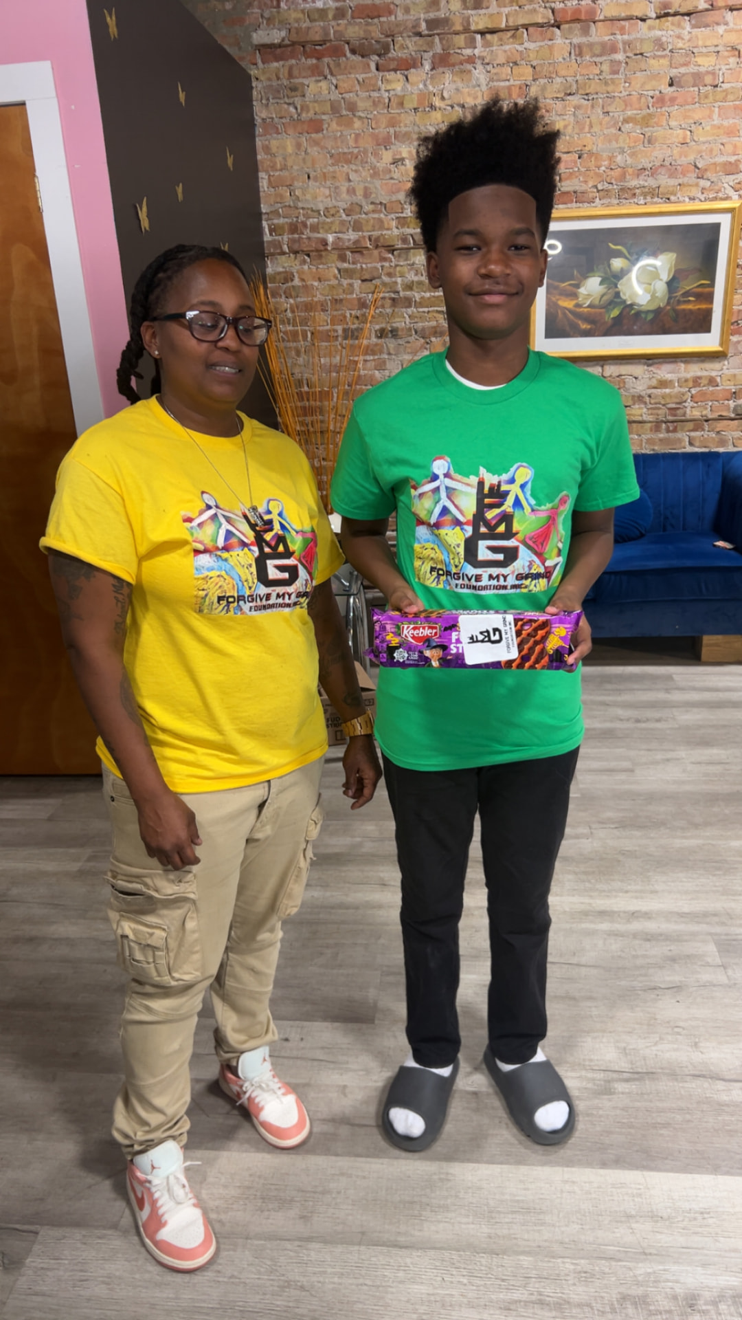 A mother and her son in Forgive My Grind shirts holding a box of treats